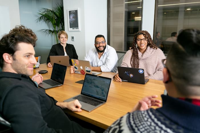 4 people working on their computers smiling at the office. spanish lessons in toronto meaningful lessons