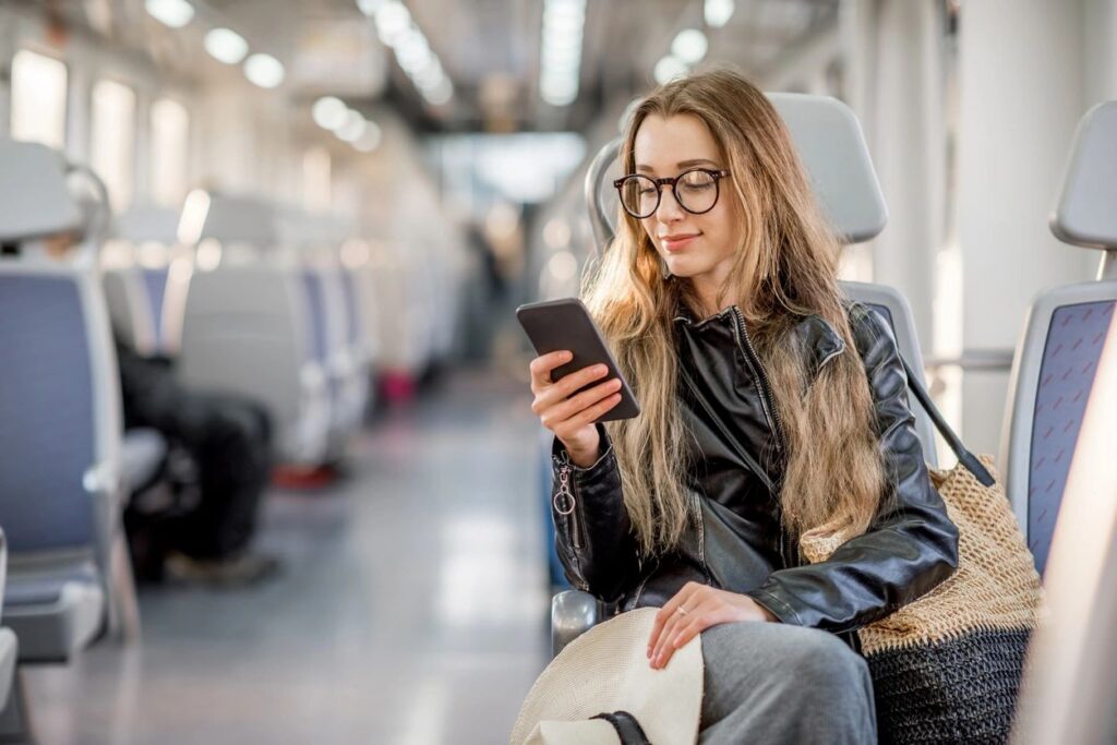 Woman sitting in the subway checking her phone.